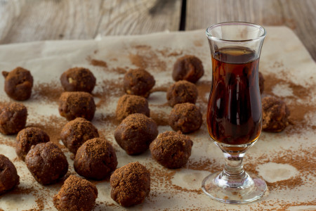 Small glass of cognac and homemade candies wooden table